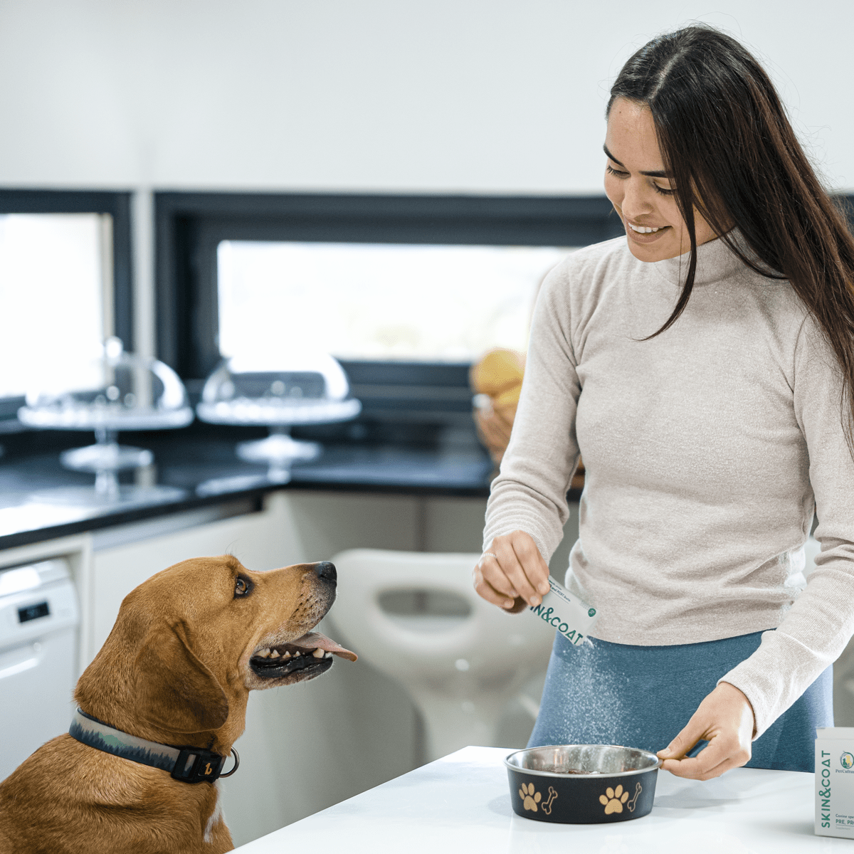Woman giving calming treat to a seated beagle in a living room setting.